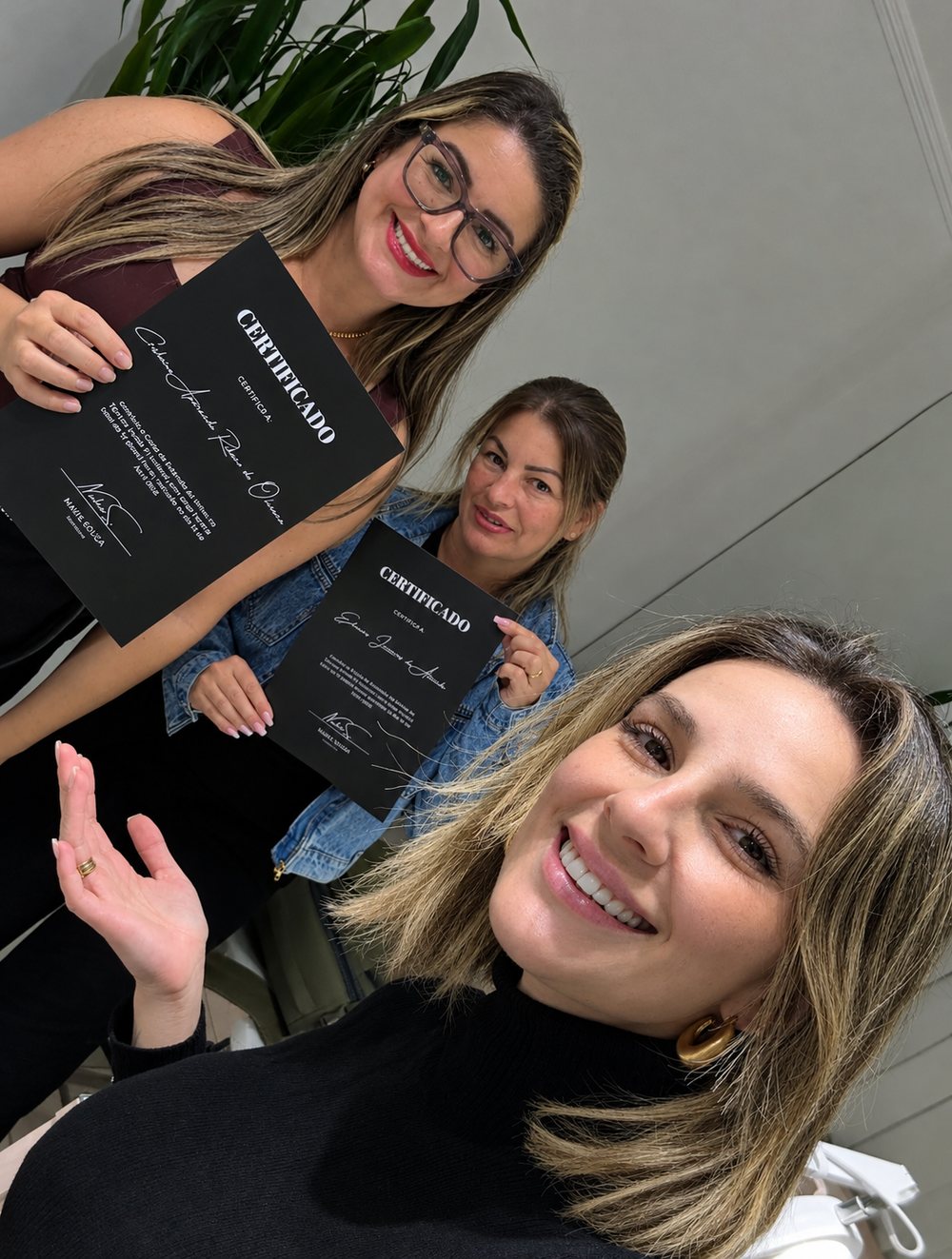 Núbia com duas alunas segurando os certificados do curso